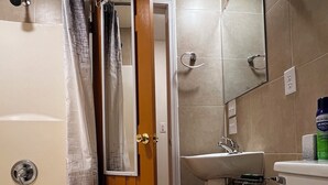 Un bany amb banyera, vàter, rentapel i plat de dutxa.