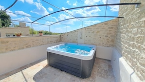 A hot tub on a rooftop terrace with stone walls and a clear sky. - Domainde des Preyauts, le Mazet (Caromb)