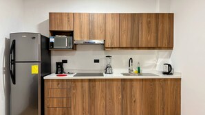 Uma cozinha moderna com armários de madeira, geladeira de aço inoxidável, micro-ondas, cafeteira, liquidificador e pia com torneira.