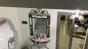 A marble-floored hallway with a decorative mirror, a small table with toiletries, and a staircase. - Maison (Médenine)