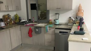 A compact kitchen with a sink, a blender, and a large vase on the counter. - Maison (Médenine)