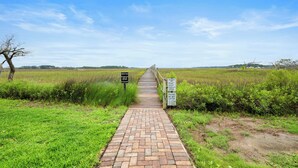 Un camino pavimentado que atraviesa un campo cubierto de hierba, con señales que indican un área de picnic y una política contra la basura.