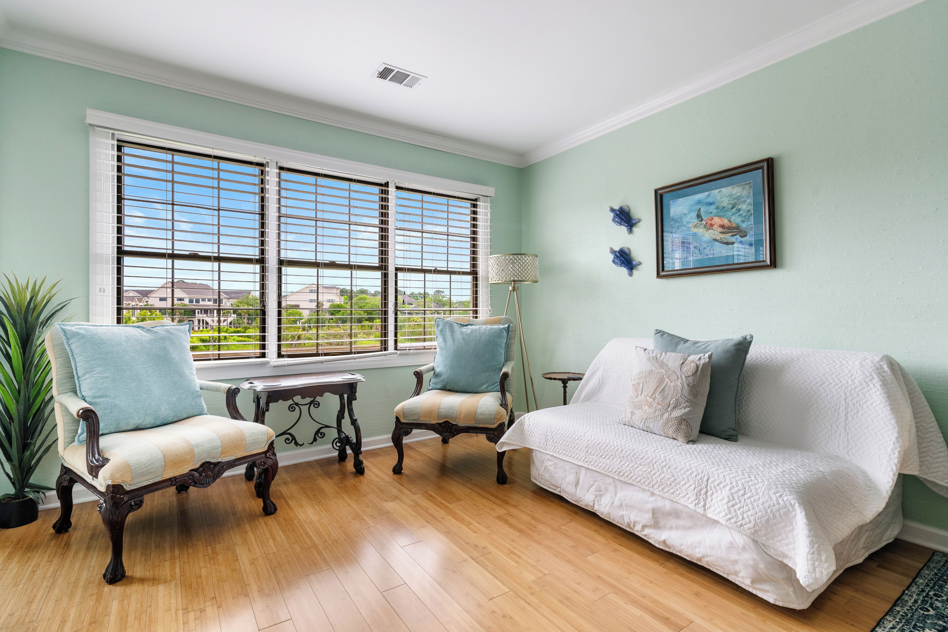 A room with a white sofa, two armchairs, a small table, and a potted plant.
