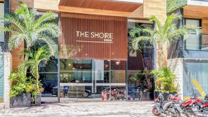 Edifici modern amb un rètol que diu “THE SHORE” i una filera de patinets aparcats a l'exterior.