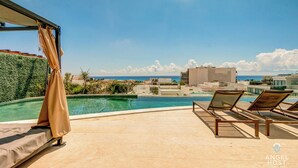 Zona de piscina al terrat amb gandules i vista a l'oceà.