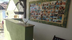 A room with a green wall, a bulletin board with photos, a small table, and a chair.