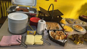 A buffet table with various food items, including bread, pastries, and a cake.
