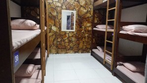 A bunk room with stone walls, bunk beds, and a small framed picture on the wall.