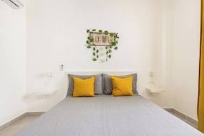 Een slaapkamer met een bed, twee nachtkastjes, een wandlamp en een decoratief bordje met een plant.