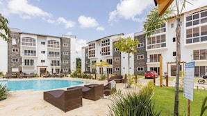 A hotel with a swimming pool, outdoor seating, and a sign indicating a social and pool area. - Bamboo Apartamento Las Terrenas (Las Terreras)