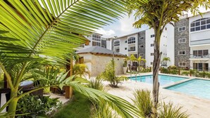 A hotel with a swimming pool, surrounded by lush greenery and palm trees. - Bamboo Apartamento Las Terrenas (Las Terreras)
