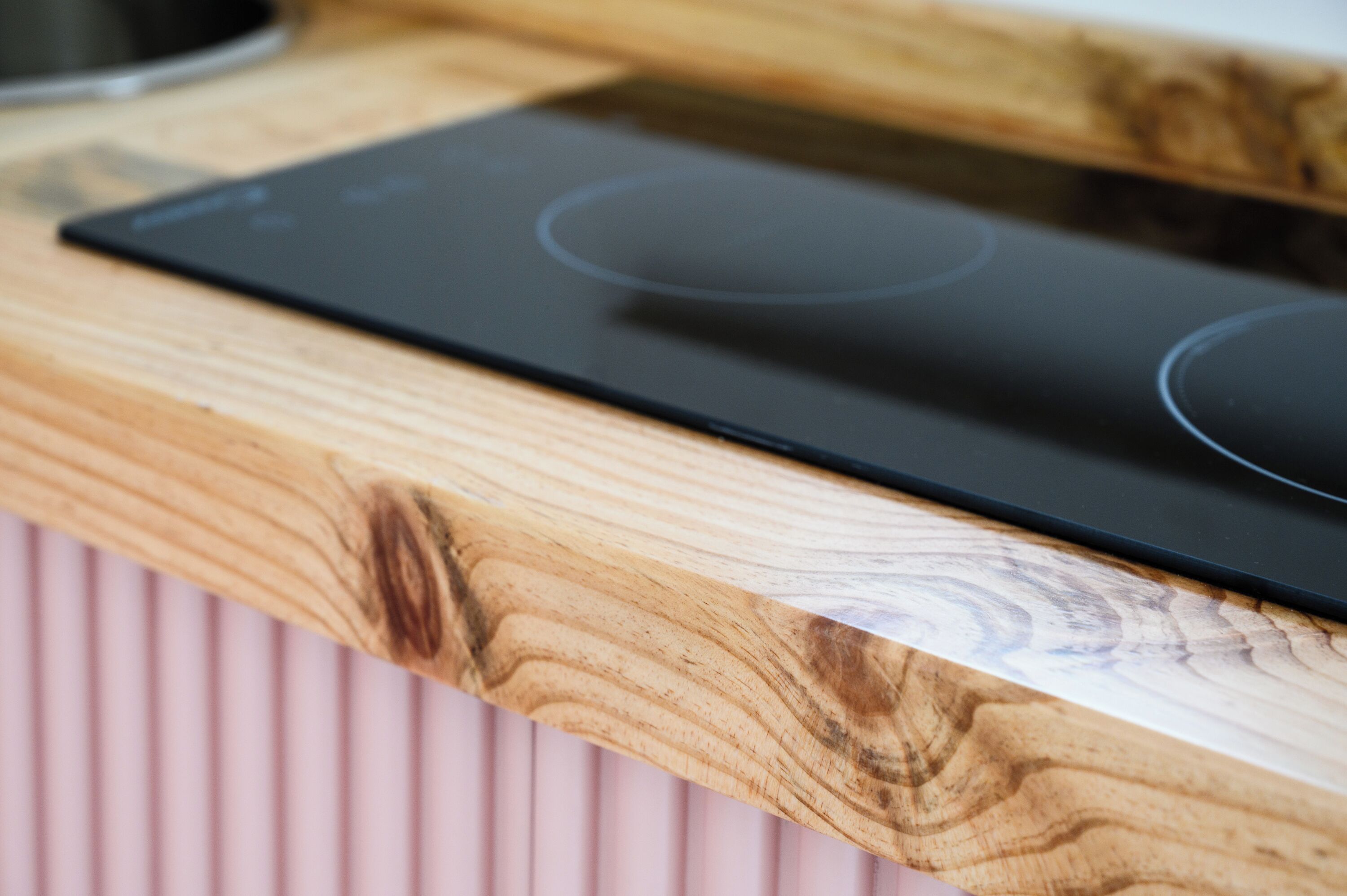 A kitchen with a black induction cooktop on a wooden countertop.