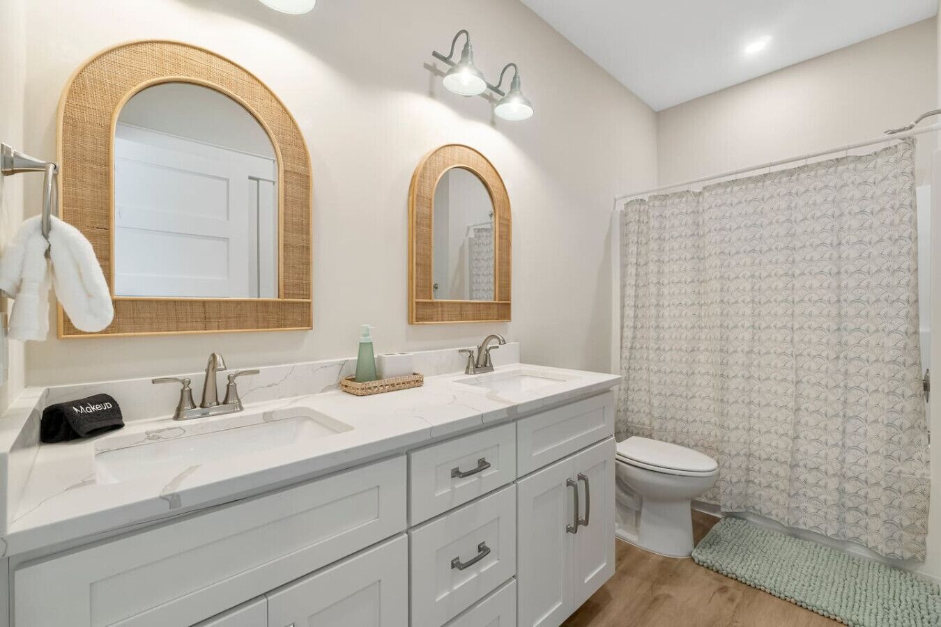 Une salle de bain avec deux lavabos, des toilettes et un rideau de douche.
