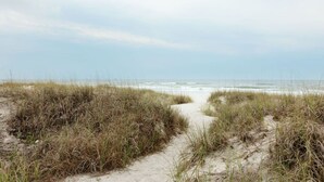 A sandy beach path leading to the ocean, surrounded by grassy dunes. - Large Home~Short Walk to Beach+Saltwater Pool l Sleeps 24 (Panama City Beach)