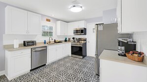 A modern kitchen with white cabinets, a stainless steel refrigerator, a microwave, and a dishwasher. - 2680- Space Cadet, Single Level, Big Yard, Large Living Area, Pet & Kid Friendly (Jacksonville)