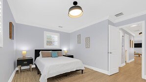 A bedroom with a bed, nightstands, a ceiling light, a window with blinds, and a door leading to another room. - 2680- Space Cadet, Single Level, Big Yard, Large Living Area, Pet & Kid Friendly (Jacksonville)