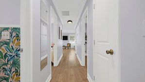 A hallway with white walls, wooden flooring, and a door with a brass doorknob. - 2680- Space Cadet, Single Level, Big Yard, Large Living Area, Pet & Kid Friendly (Jacksonville)