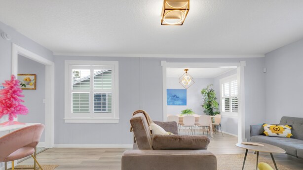 A spacious living room with a beige sofa, a yellow armchair, and a dining area with a white table and chairs. - 917- San Marco Sky Cottage, Pets OK, Near Arenas & Hospitals (Jacksonville)