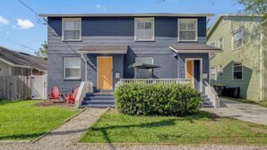 A two-story residential building with a front porch, a small front yard, and a visible garage. - 917- San Marco Sky Cottage, Pets OK, Near Arenas & Hospitals (Jacksonville)