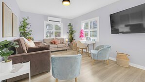 Un salon moderne avec un canapé marron, un fauteuil bleu et un coin repas comprenant une table et des chaises.