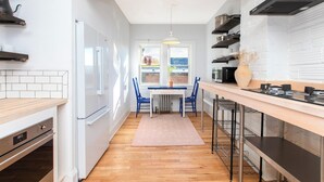 A modern kitchen with white cabinetry, a central island, and a view to the outside. - Modern Loft in Historic Birdtown - Unit 8 (Lakewood)