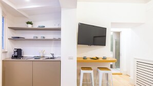Una cucina moderna con una televisione a schermo piatto, sgabelli di legno e un piccolo angolo pranzo.