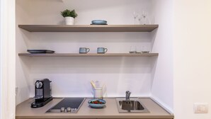 Una cucina moderna con una macchina da caffè, una ciotola di frutta e un lavello.