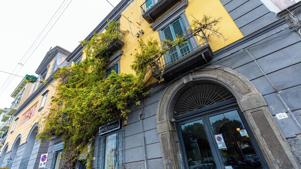 Un edificio con facciata gialla, diverse finestre e un'entrata ben visibile.