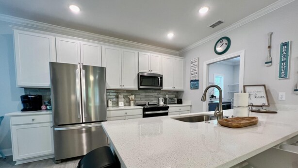 A modern kitchen with white cabinetry, stainless steel appliances, and a speckled countertop. - Private Pool, Pet-Friendly, New 3BR Home in Cherry Grove (North Myrtle Beach)