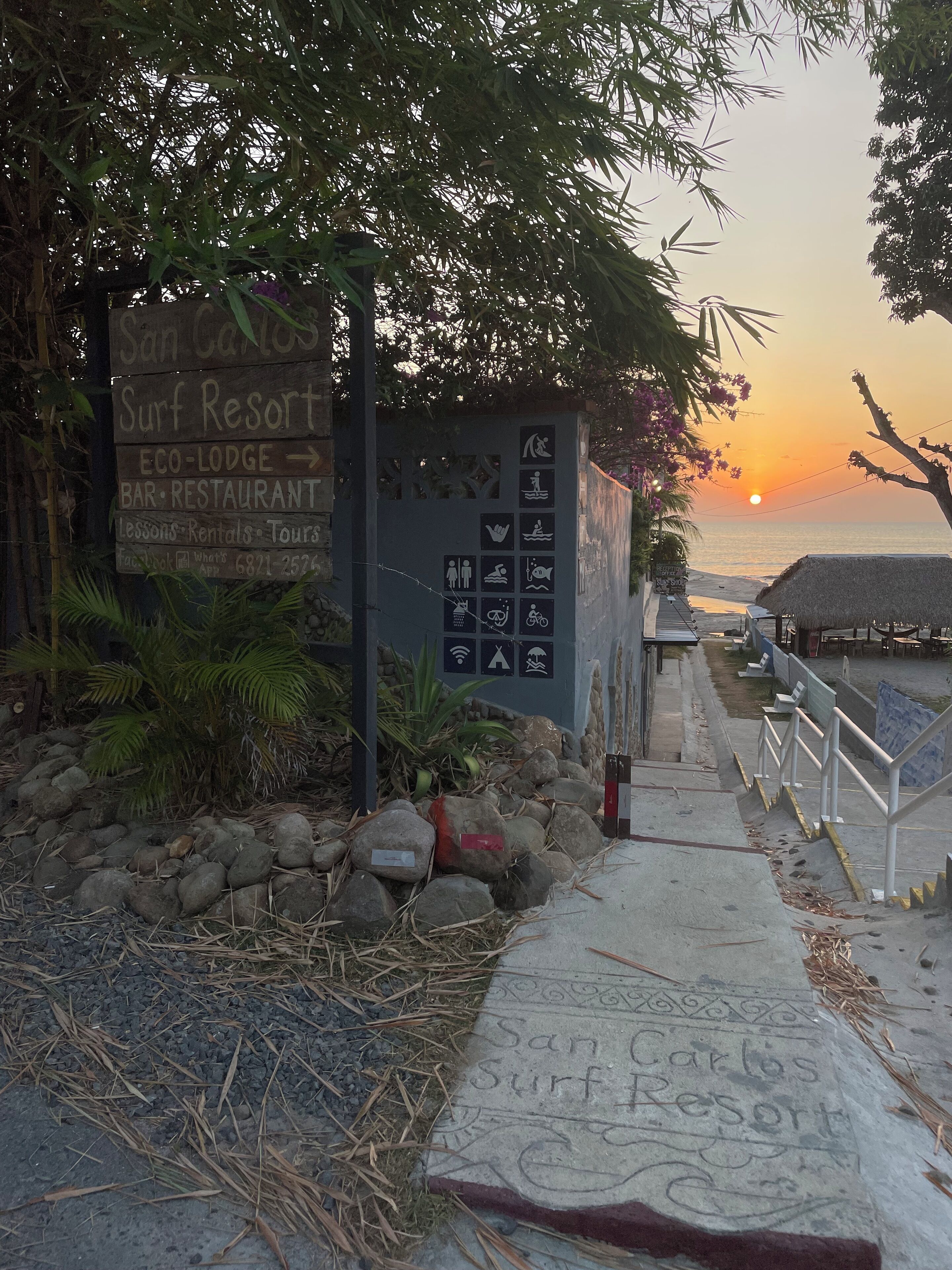 A sign for San Carlos Surf Resort with amenities like a bar, restaurant, and eco-lodge.