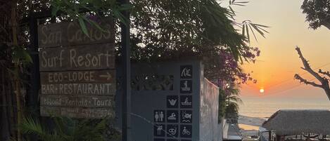 A sign for San Carlos Surf Resort with amenities like a bar, restaurant, and eco-lodge.