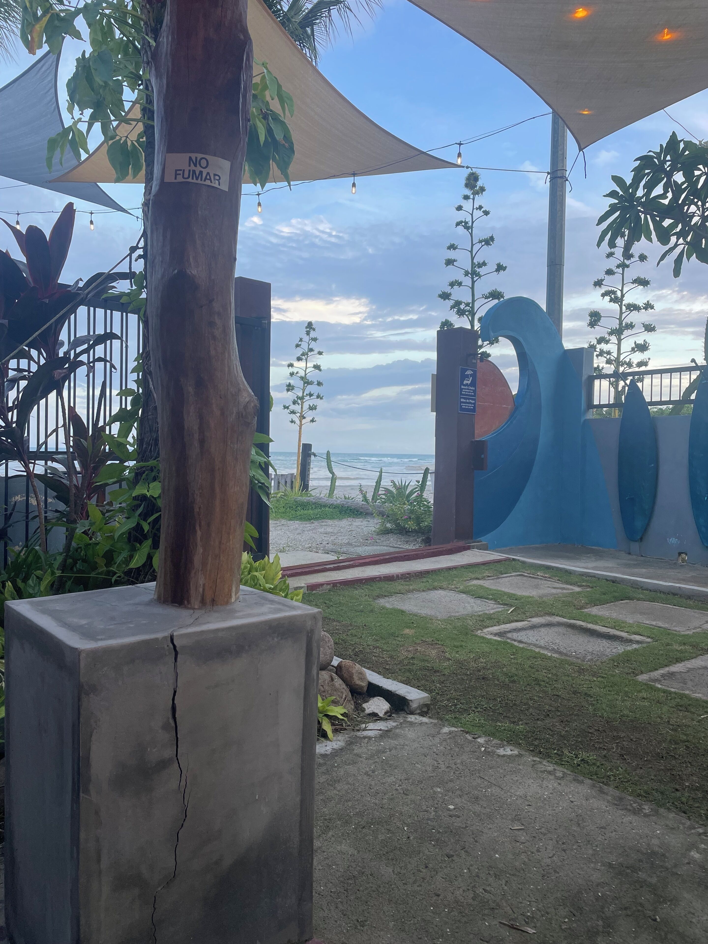 A beachfront property with a concrete structure, a 'NO FUMAR' sign, and a view of the ocean.