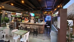 An outdoor restaurant with a bar area, white plastic chairs, and tables.