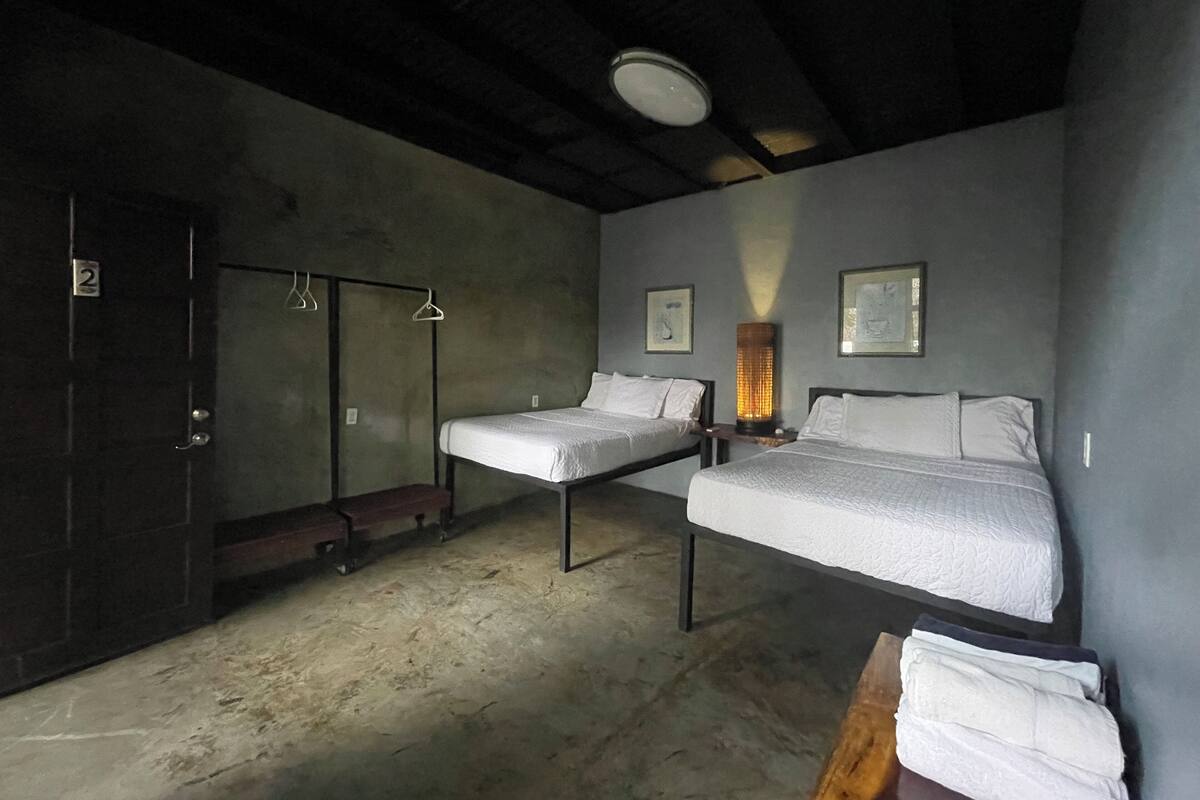 A room with two beds, a bench, a heater, and a door marked with the number 2.