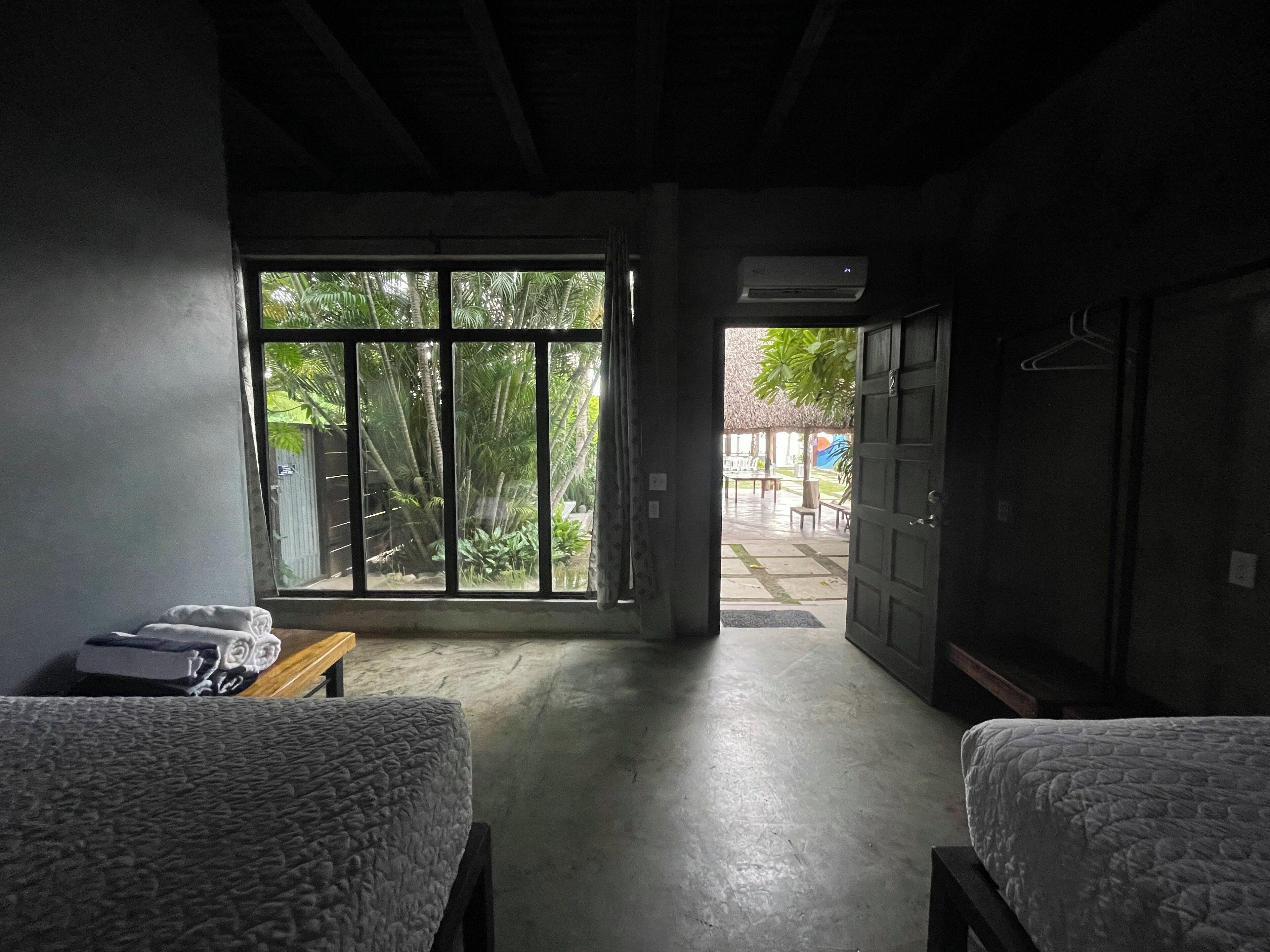 Een kamer met twee bedden, een raam en een airconditioning.