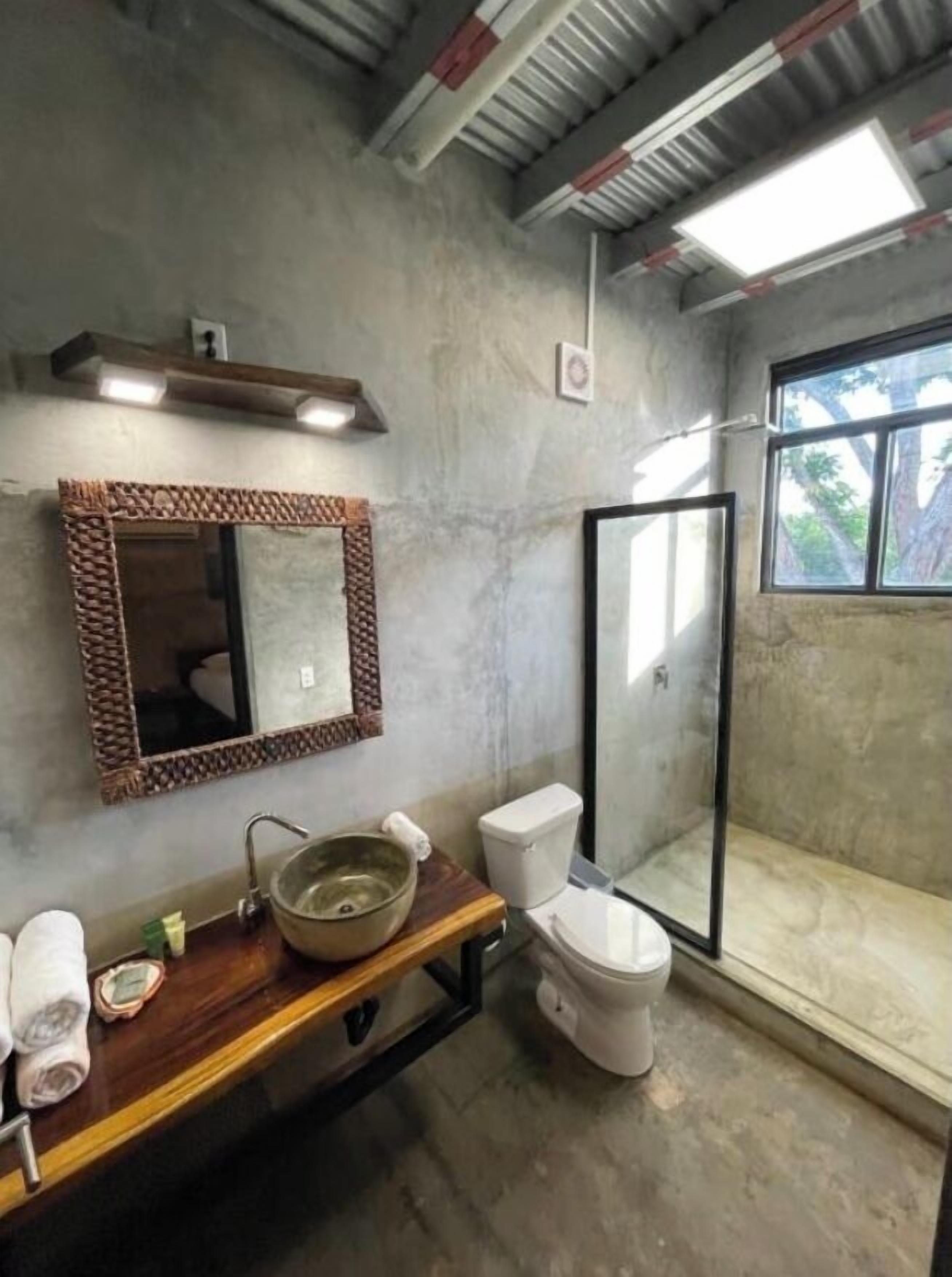 Un baño con tocador de madera, un espejo grande, un inodoro y una cabina de ducha de vidrio.