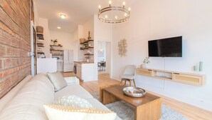 Een moderne woonkamer met een bank, salontafel en een aan de muur bevestigde televisie.