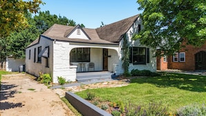 A single-story house with a stone facade, a covered porch, and a well-maintained lawn.