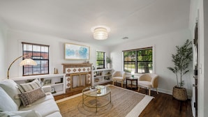 A living room with a sofa, coffee table, fireplace, and large windows.