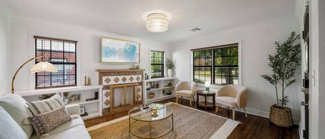 A living room with a sofa, coffee table, fireplace, and large windows.