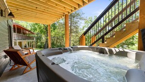 Un jacuzzi con cubierta de madera, una silla y una escalera que conduce a un nivel superior.