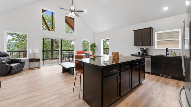Una cocina amplia con una isla grande, armarios oscuros y vistas al exterior.