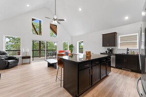 A spacious kitchen with a large island, dark cabinetry, and a view of the outdoors. - C04  4 BR Waterfront Cabin w/ Pool + Swim & Boat dock (Branson West)