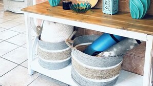 Una consola de madera con jarrones decorativos, un cartel de madera redondo y cestas tejidas debajo.