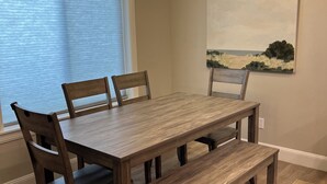 A dining area with a wooden table, four chairs, a bench, and a chandelier. - Cozy all season retreat, center of town! (Garden City)