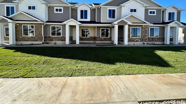 A row of townhouses with a stone facade, multiple windows, and a well-maintained lawn. - Cozy all season retreat, center of town! (Garden City)