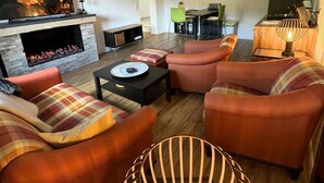 Una sala de estar con chimenea, sofá, televisor y comedor.