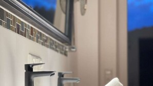 Un baño moderno con un lavabo negro, un espejo y una encimera de madera.