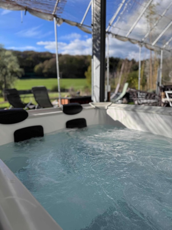 A hot tub with a view of a green landscape.