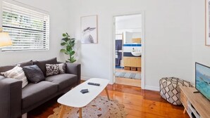 A modern living room with a grey sofa, a white coffee table, and a television. - Charming UNIT in the heart of New Farm, BNE. (New Farm)